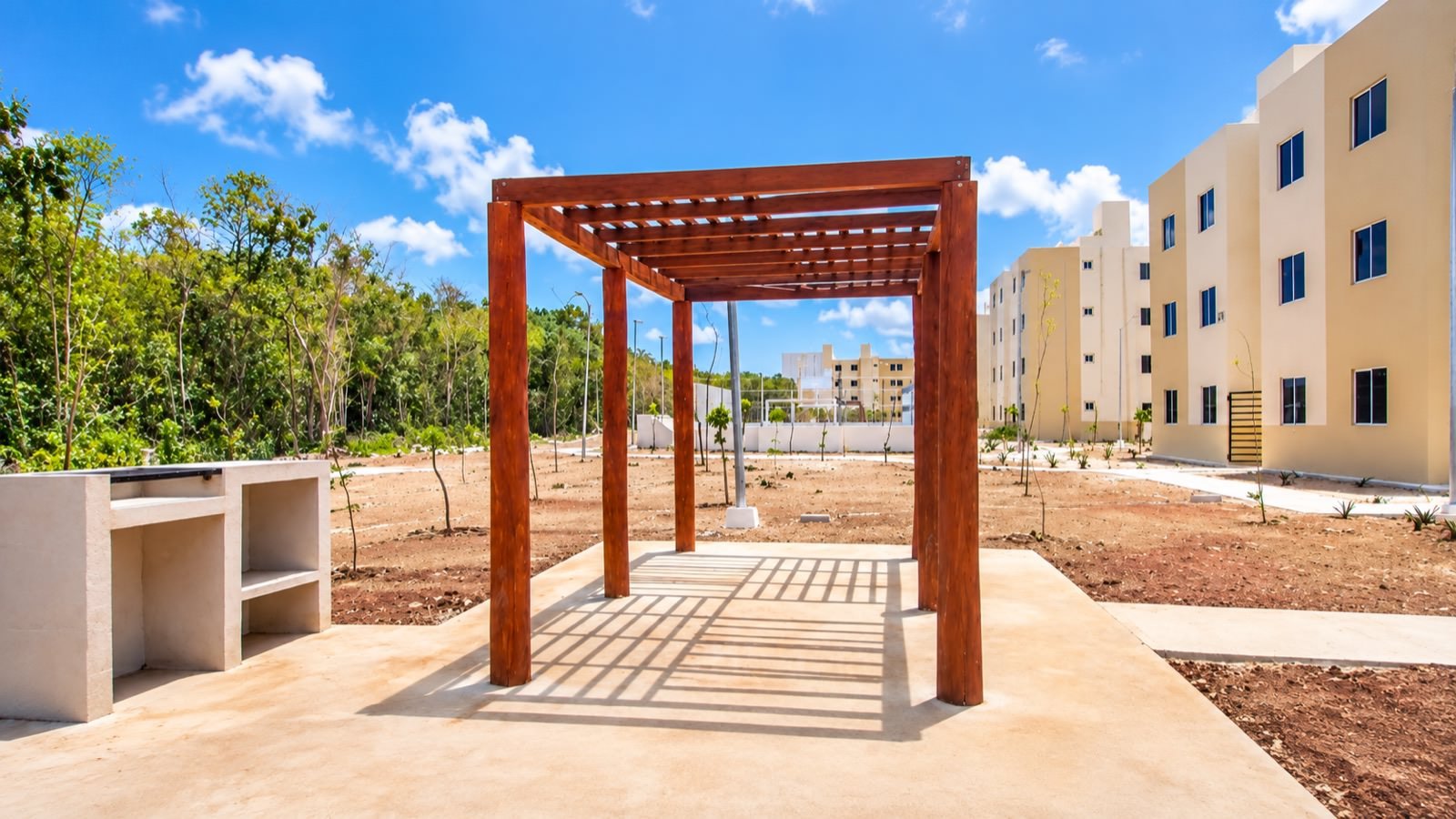 Pérgola de madera con acabado barnizado y asador de muros de block en área común de Aura Nova
