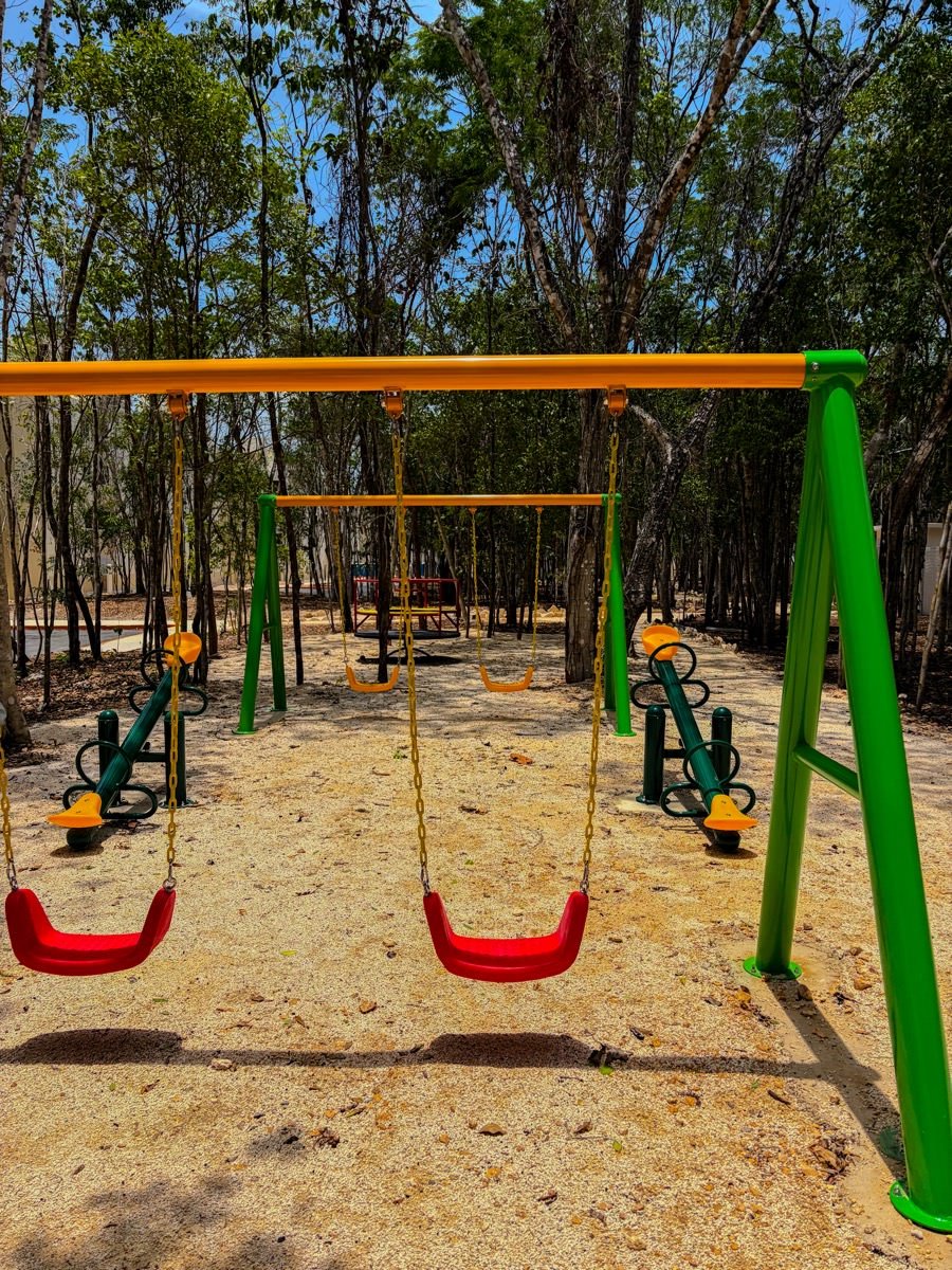 Juegos infantiles y columpios con piso de arena fina en Aura Nova