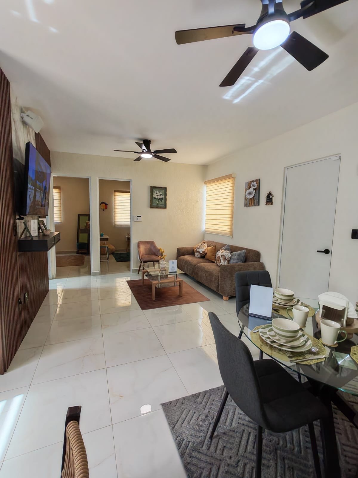 Sala y comedor de concepto abierto del Modelo Aura Mar, con sala, mesa de comedor y acceso a las recámaras